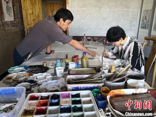 圖為2020年8月下旬，敦煌“80后”畫家張杰龍(左)在為云南麗江“學(xué)生”莫北講解敦煌壁畫的繪畫技巧?！●T志軍 攝