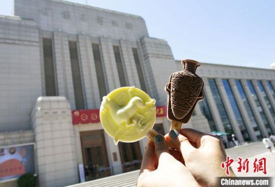 2021年7月30日，游客手拿“銅奔馬”“彩陶瓶”造型的雪糕，在甘肅省博物館前拍照打卡。　高展 攝