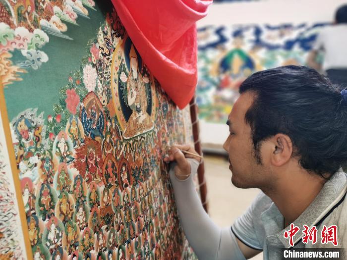 圖為更登才讓的徒弟繪畫唐卡?！?zhí)砀?攝