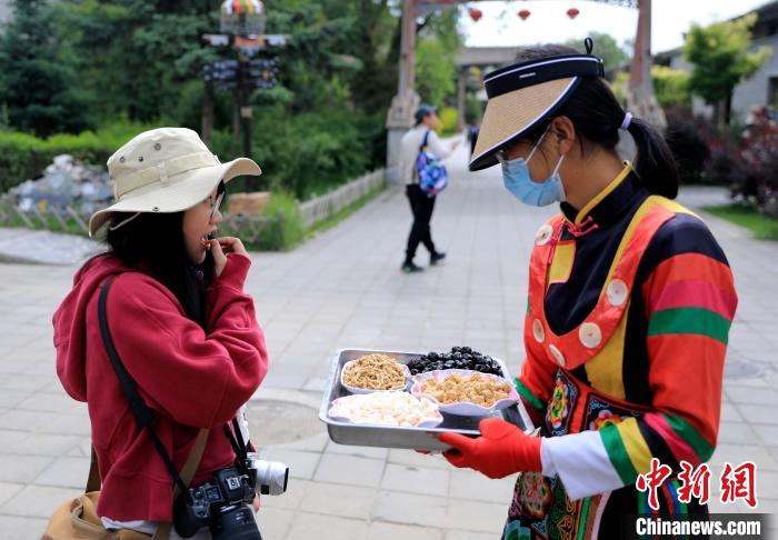 圖為身穿土族服飾的女性介紹當?shù)靥厣〕??！⊙Φ?攝