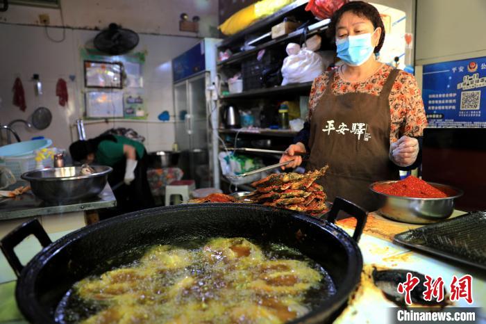 圖為平安驛·河湟民俗文化體驗(yàn)地內(nèi)的商戶炸干板魚?！⊙Φ?攝