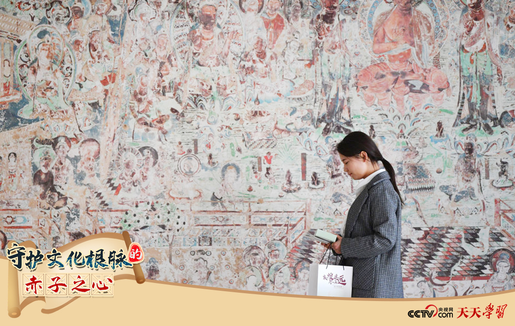 2023年4月25日，敦煌研究院文物數(shù)字化保護團隊創(chuàng)意營銷人員廖雪婷從一幅高保真復(fù)制壁畫前走過。