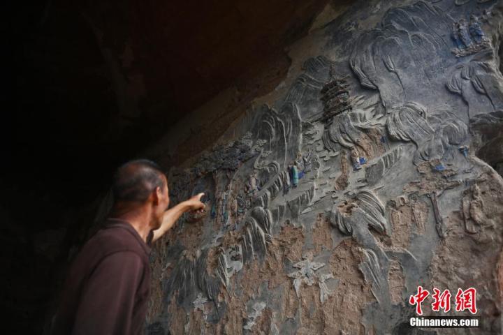 7月15日，甘肅省平?jīng)鍪袥艽h百里石窟長廊羅漢洞石窟內(nèi)，該窟文保員郭建平介紹窟內(nèi)石刻彩繪壁畫。郭建平家中三代人曾自發(fā)保護(hù)羅漢洞石窟。羅漢洞石窟遺存40余個(gè)窟龕，以北魏至清代風(fēng)格為主。中新社記者 李亞龍 攝