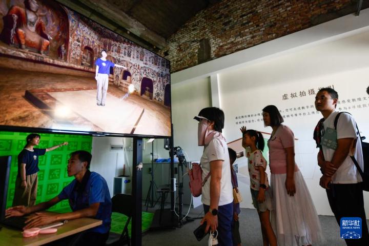 7月22日，游客體驗(yàn)“尋境敦煌——數(shù)字敦煌沉浸展”后，在虛擬演播廳拍攝一段真人與洞窟虛擬場景交互的視頻。新華社記者 郎兵兵 攝</p>
<p>