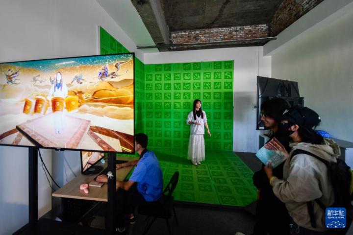 7月22日，游客體驗(yàn)“尋境敦煌——數(shù)字敦煌沉浸展”后，在虛擬演播廳拍攝一段真人與洞窟虛擬場景交互的視頻。新華社記者 郎兵兵 攝</p>
<p>